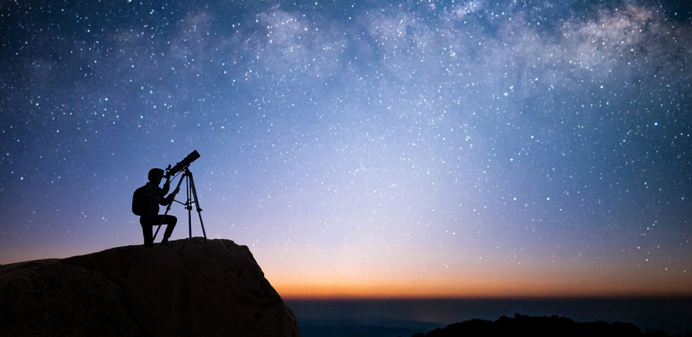 man using telescope under the milky way