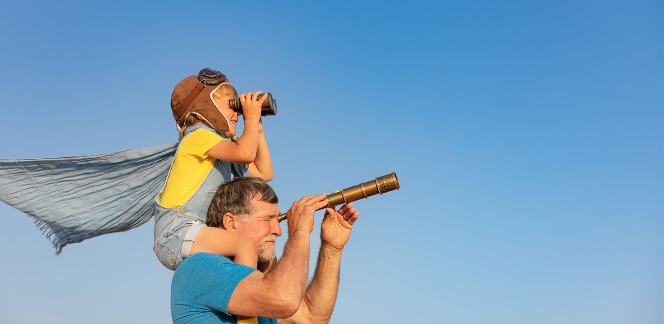 young man on father's shoulders looking through binoculars
