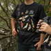 Person wearing a black t-shirt with bird illustrations in a natural setting