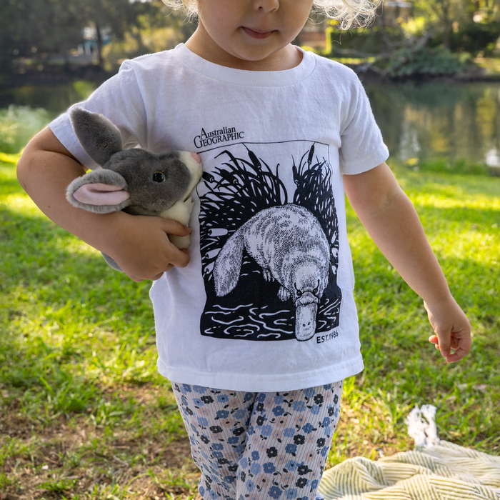 Child wearing a t-shirt with a platypus design outdoors