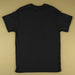 A plain black short-sleeve t-shirt laid flat against a solid beige background, showing the back view.