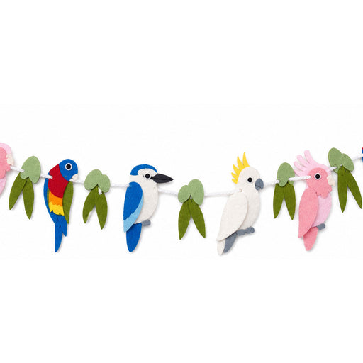A felt bird garland featuring colorful birds including a red, yellow, and blue parrot, a blue and white kingfisher, a white cockatoo with a yellow crest, and a pink cockatoo, hanging on a white string against a white background.