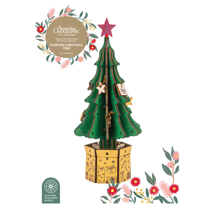 A wooden 3D Christmas tree model in a gift box base, shown on a white background with decorative floral graphics and branding text for Australian Geographic.