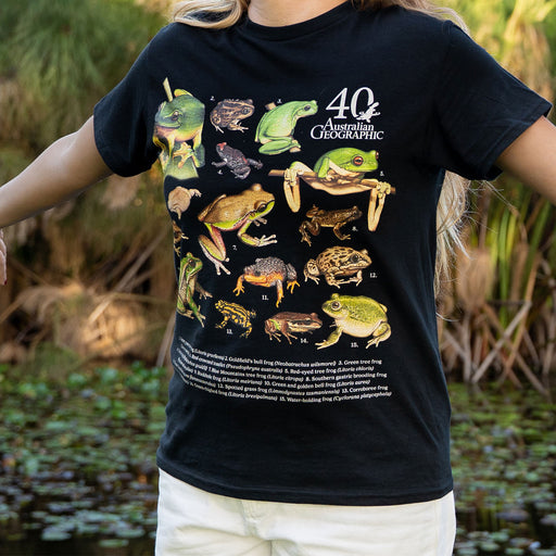 Person wearing a black t-shirt with illustrations of Australian frogs, standing in a natural setting.