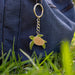 Turtle keychain attached to a blue bag on grass
