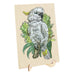A rectangular wooden jigsaw puzzle board featuring an illustrated white cockatoo perched among green leaves, displayed on a small wooden stand against a plain white background.