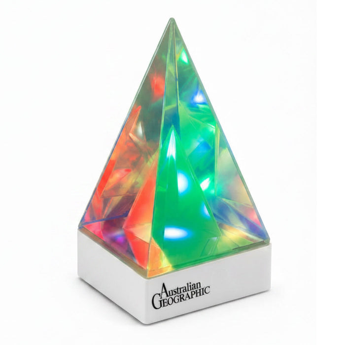 A faceted crystal pyramid lamp with a white base printed with the 'Australian Geographic' logo, emitting colorful light through its transparent geometric structure.