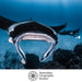 Underwater photograph of a giant manta ray swimming through deep blue ocean water, with a second manta ray and coral reef in the background. The Australian Geographic Society logo is printed at the bottom on a white band.