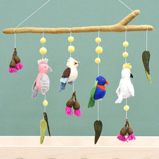 Colorful bird-themed mobile with hanging toys against a green background