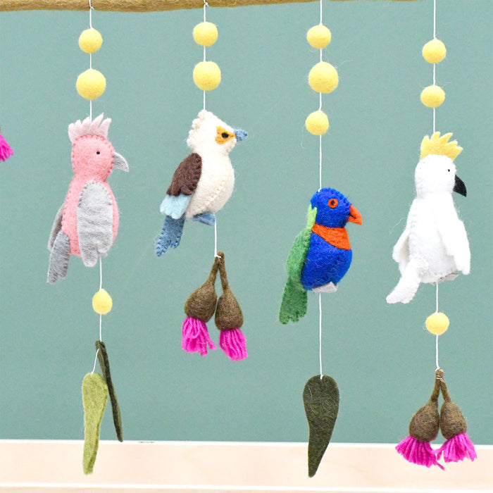 Colorful bird-themed mobile with hanging toys against a light blue background