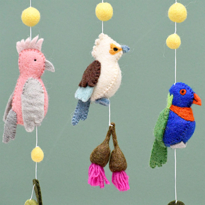 Colorful bird-themed mobile with pink, brown, and blue birds on a plain background