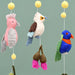 Colorful bird-themed mobile with pink, brown, and blue birds on a plain background