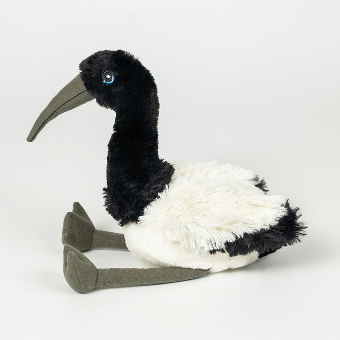 A plush stuffed bird toy with a black head and neck, white body, and gray beak and legs, photographed on a clean light gray studio background.