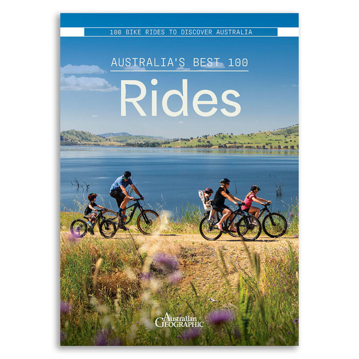 Australian Geographic magazine cover titled 'Australia's Best 100 Rides', featuring a scenic photograph of cyclists riding along a path by a lake with the text '100 Bike Rides to Discover Australia' at the top.