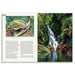 An open printed travel guide or magazine spread showing a large scenic photograph of a waterfall in a lush green forest on the right page, with text and a smaller inset map on the left page.