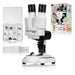 Bresser Biolux 2X educational toy microscope set, featuring a white and black binocular microscope, a clear specimen storage box filled with small rocks, a slide tray, and a colorful retail packaging box in the background.