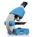 A blue and gray compound microscope with black knobs and silver objective lenses, shown on a clean white background with a subtle reflection.