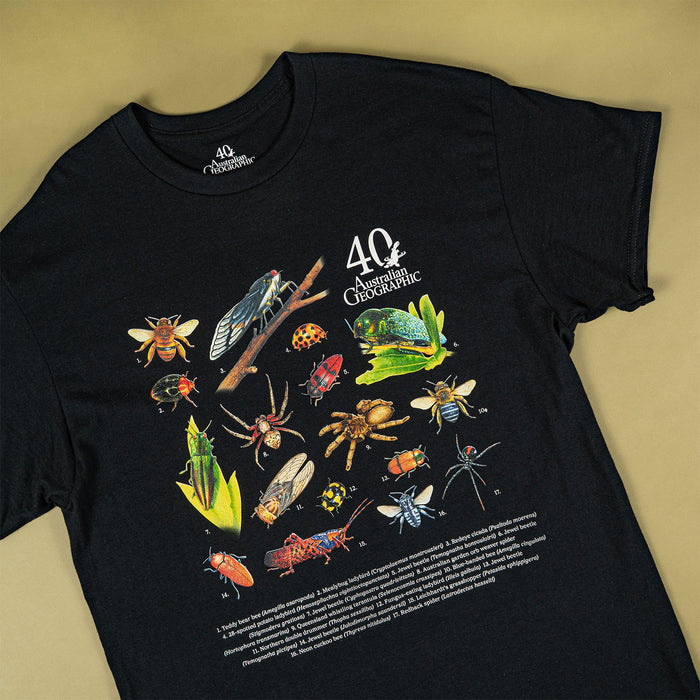 A black short-sleeve graphic T-shirt laid flat on a warm beige background. The shirt features a large colorful print of various insects and spiders, with the text '40th Anniversary' and 'Australian Geographic' on the chest.