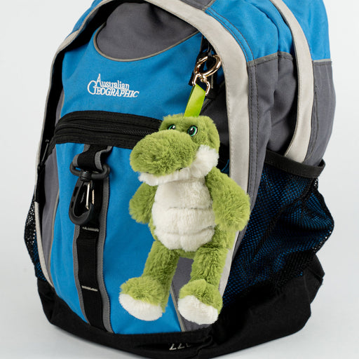 Blue and gray backpack with a green plush crocodile toy attached on a white background