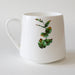 White mug with green leaf design on a white background