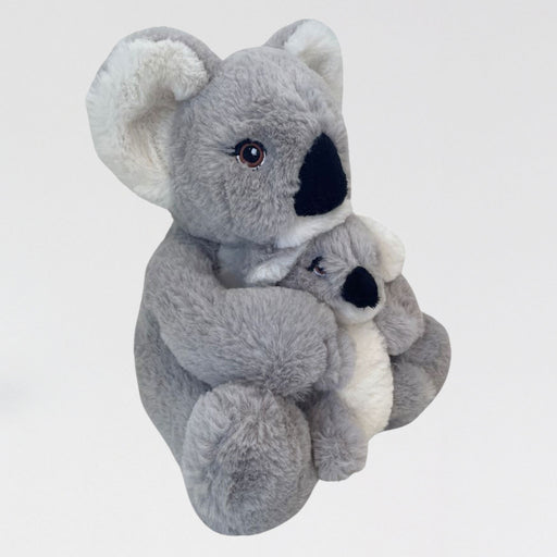 Plush toy koala holding another plush toy on a light gray background