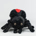 Black plush spider toy with red marking on a white background