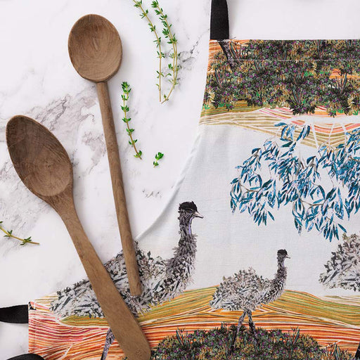 Wooden spoons on a marble surface with a decorative towel featuring emus in the background.