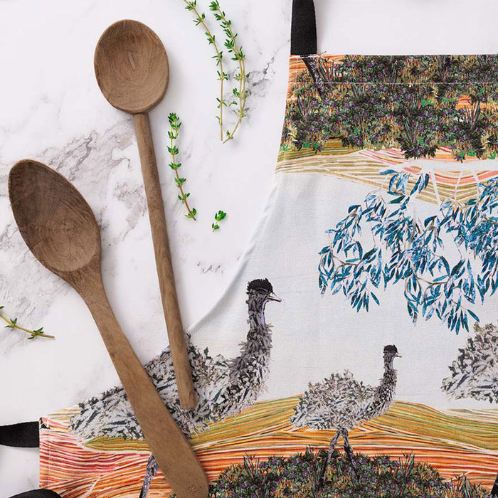 Wooden spoons on a marble surface with a decorative towel featuring emus in the background.