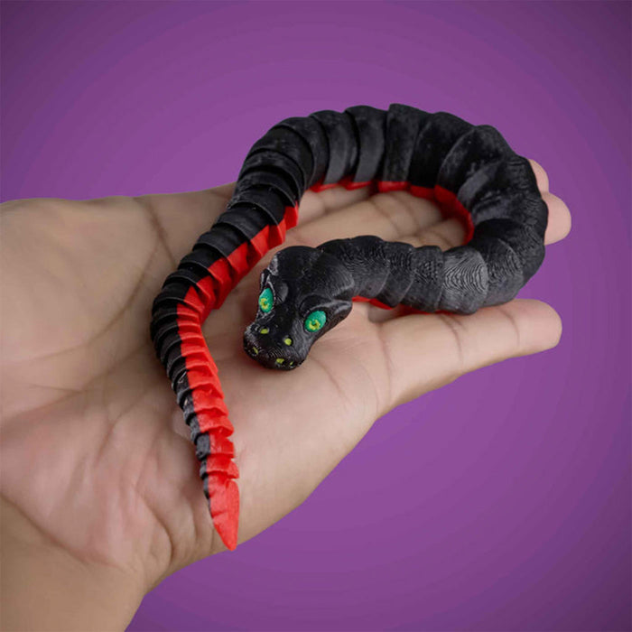 Black and red snake-shaped toy held in a hand against a purple background