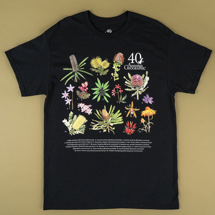 A black short-sleeve graphic t-shirt featuring a colorful botanical illustration of Australian flowers and plants, with the text '40th Anniversary' and 'Australian Geographic' printed on the chest, laid flat on a beige background.