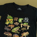 Black t-shirt with illustrations of Australian frogs and 40th anniversary logo on a beige background