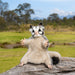 Stuffed animal sugar glider on a log with a natural landscape background