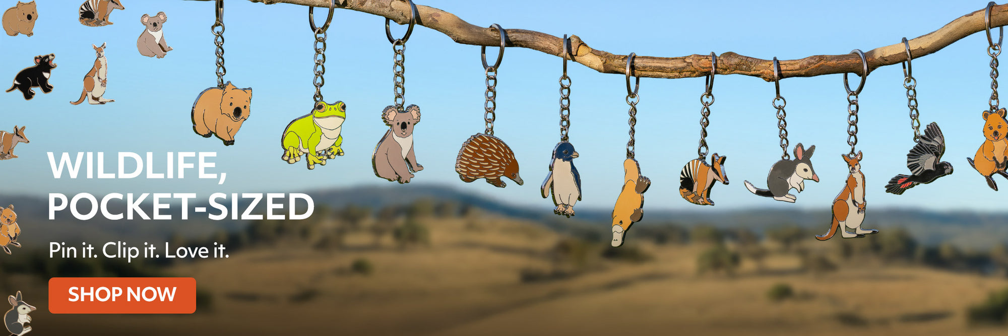Collection of small animal figurines hanging from a branch with a scenic background.