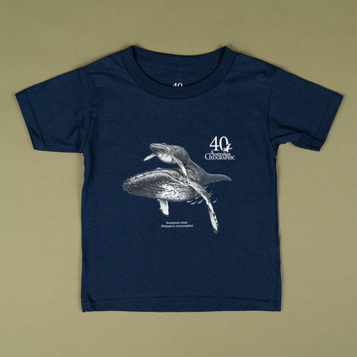 A navy blue short-sleeve t-shirt with a graphic print of a humpback whale and the text '40 Years Australian Geographic' on the front, laid flat on a solid olive-beige background.