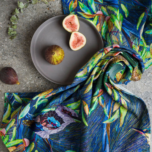 Figs on a gray plate with a colorful fabric draped over a concrete surface