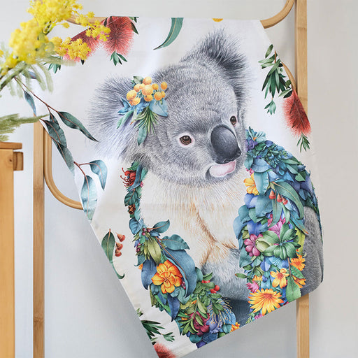 Towel with a koala design surrounded by flowers and leaves on a wooden rack.