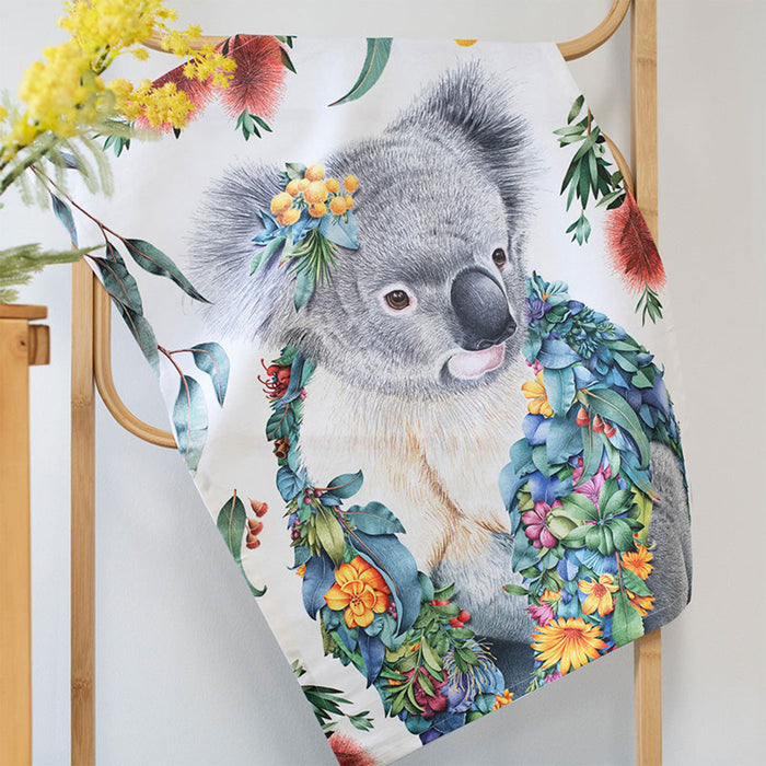 Towel with a koala design surrounded by flowers and leaves on a wooden rack.