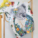 Towel with a koala design surrounded by flowers and leaves on a wooden rack.