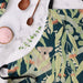 Apron with koala and eucalyptus design on a marble surface with kitchen items.