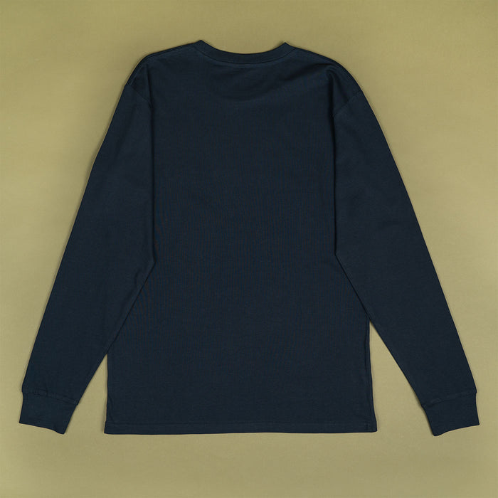 A dark navy blue long-sleeve t-shirt shown from the back, laid flat on a solid beige background.