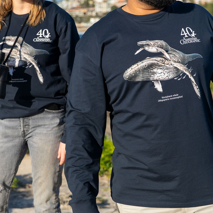 Two people wearing matching navy long-sleeve T-shirts with a large gray whale graphic and white '40th Australian Geographic ' text on the chest, photographed outdoors.