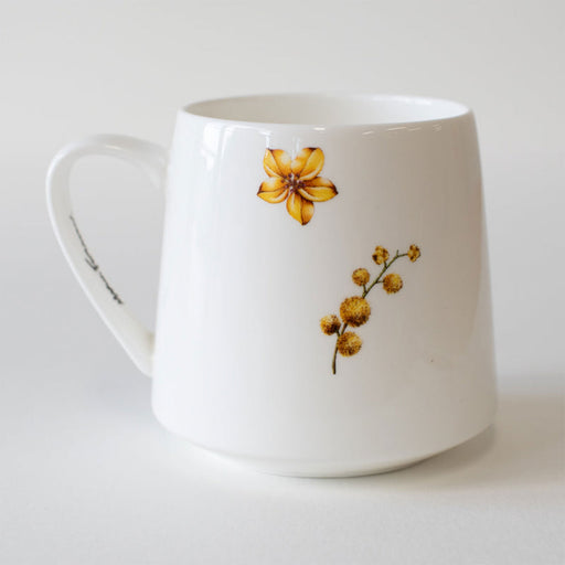 White mug with yellow floral design on a white background