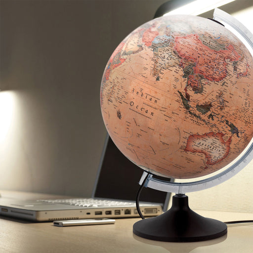 World globe on a desk with a laptop in the background