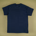A plain navy blue short-sleeve t-shirt laid flat against a solid beige background.