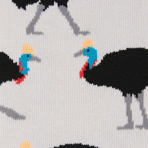 Close-up of a knit fabric with a repeating pattern of black cassowellas featuring bright blue, red, yellow, and gray details on a light background.