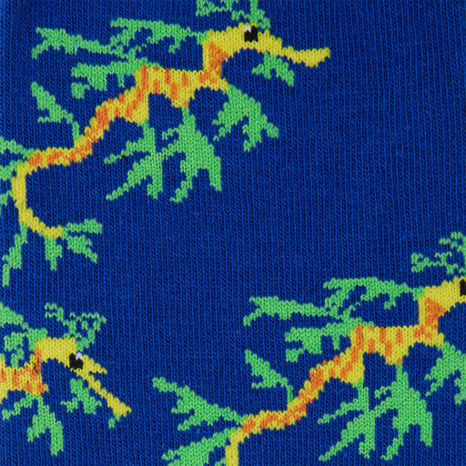 A close-up of a knitted fabric featuring a repeating pattern of leafy sea dragons in yellow and orange on a bright blue background.