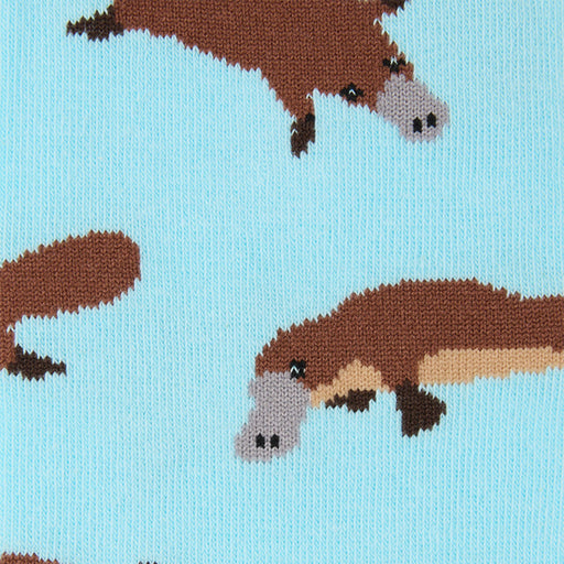 Close-up of a knitted fabric with a repeating platypus pattern on a light blue background.