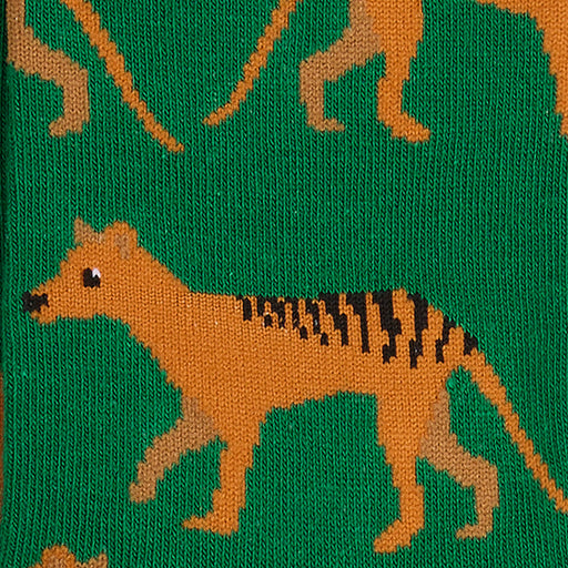 Close-up of a knitted fabric featuring an orange Tasmanian tiger with black stripes on a green background, with partial kangaroo tails visible at the top.
