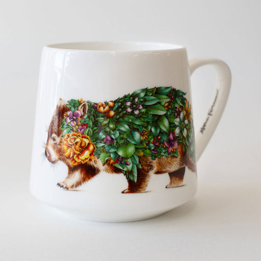 White mug with a decorative design of a wombat covered in flowers and leaves on a white background