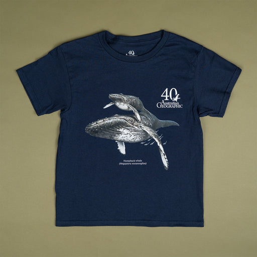 A navy blue short-sleeve t-shirt with a graphic print of two humpback whales and the text '40th Australian Geographic' and 'Humboldt Whale National Marine Sanctuary' on the front, laid flat on a solid olive green background.